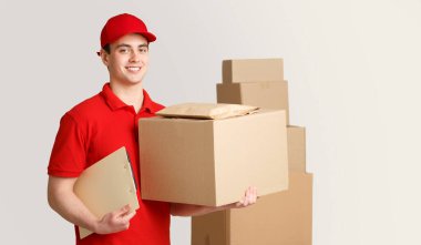 Kurye ve paket depoda. Teslimatçı elinde kutu ve tablet paketin yanında.