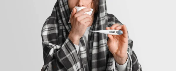 Fieber und Krankheit. Mann hustet, deckt den Mund mit Serviette zu und zeigt Thermometer mit hoher Temperatur — Stockfoto