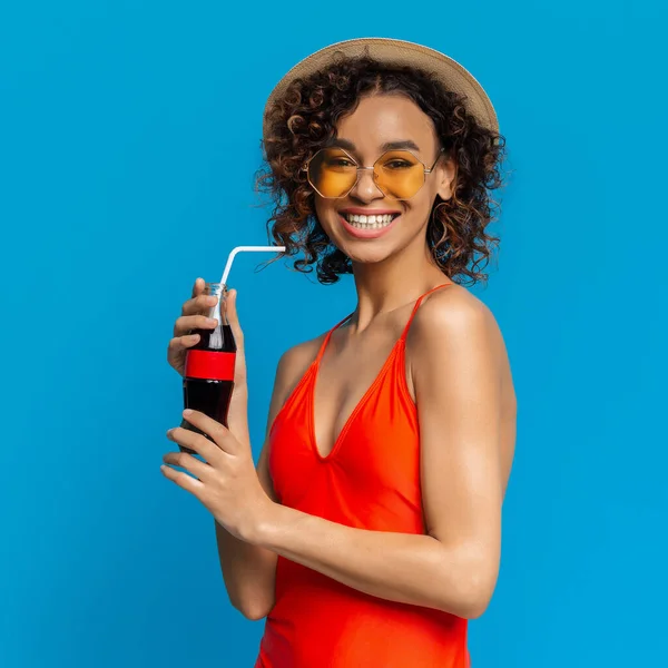 KHARKIV, UCRÂNIA - 31 de março. 2019: Menina africana positiva em roupa de banho desfrutando de refrescante bebida de verão, segurando garrafa de Coca-Cola com palha — Fotografia de Stock