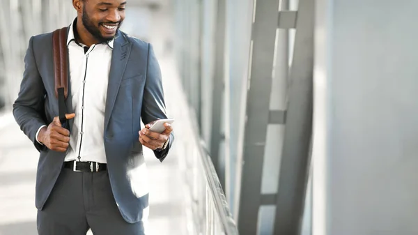 Empresario que usa el teléfono caminando con la mochila en el aeropuerto, recortado, Panorama — Foto de Stock