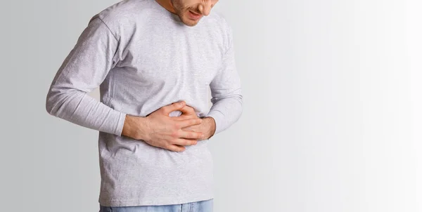 Magenprobleme. Mann drückt sich vor Schmerzen die Hände an den Bauch — Stockfoto