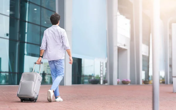 Bakre vy porträtt av man går utanför flygplatsen med resväska — Stockfoto