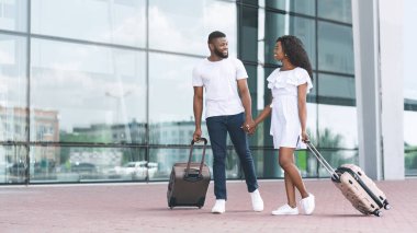 Hava Yolları Devam Ediyor. Siyah çift, el bagajlarıyla havaalanının yakınına yürüyorlar.