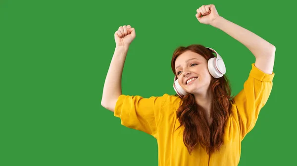 Adolescente chica disfrutando de la música en auriculares bailando sobre fondo verde —  Fotos de Stock