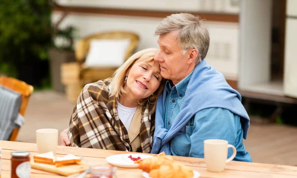 Senior kuschelt mit seiner Frau beim Frühstück auf dem Zeltplatz — Stockfoto
