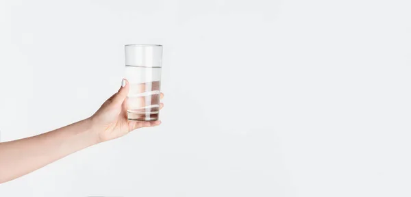 Vista recortada de niña milenaria sosteniendo un vaso de agua clara sobre fondo blanco, espacio vacío — Foto de Stock