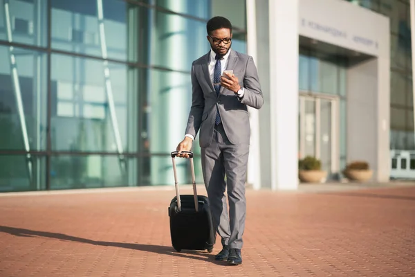 Empresario africano usando Smartphone esperando vuelo de pie en el aeropuerto — Foto de Stock