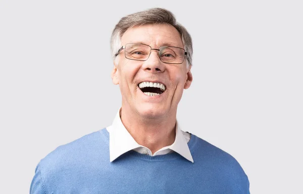 Oudere man lachen hardop poseren over grijze achtergrond — Stockfoto