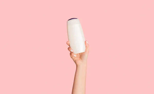 Mädchen zeigt Flasche Shampoo, Lotion oder Duschgel mit Mockup für Design auf rosa Hintergrund, Nahaufnahme — Stockfoto