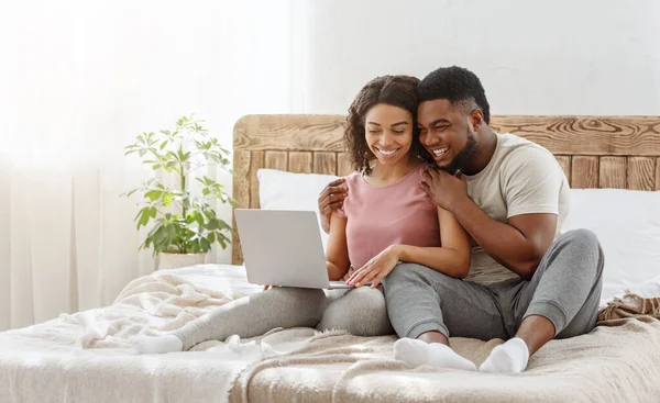 Africano hombre y mujer mirando a la pantalla del ordenador portátil y abrazos —  Fotos de Stock