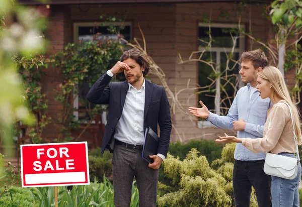 Corredor de bienes raíces con problemas tratando con clientes perturbados sobre la compra de casa nueva, al aire libre —  Fotos de Stock