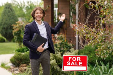 Gülümseyen emlakçı açık havada satılık ev gösteriyor. Boş boşluk