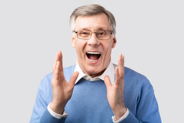 Izgatott idősebb úriember kiabálás pózol át szürke háttér — Stock Fotó