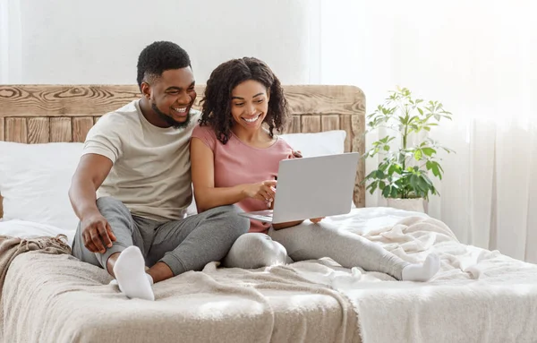 Alegre pareja negra navegar por Internet en la cama —  Fotos de Stock