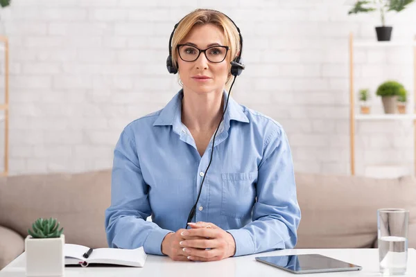 Nueva educación para el trabajo moderno. Mujer con auriculares sentada en la mesa, escuchando webinar —  Fotos de Stock