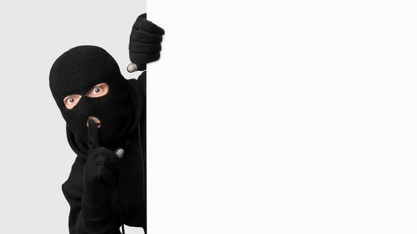 Ladrão mascarado espreitando placa branca em branco, fazendo sinal de silêncio — Fotografia de Stock