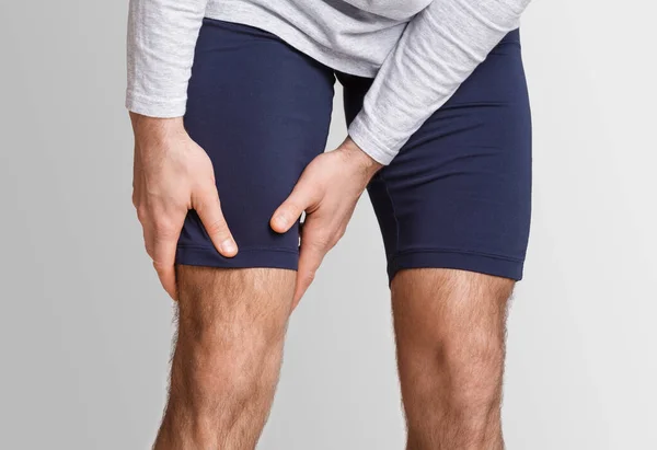 Dolor muscular en atleta. Hombre en ropa deportiva presiona sus manos a la pierna —  Fotos de Stock