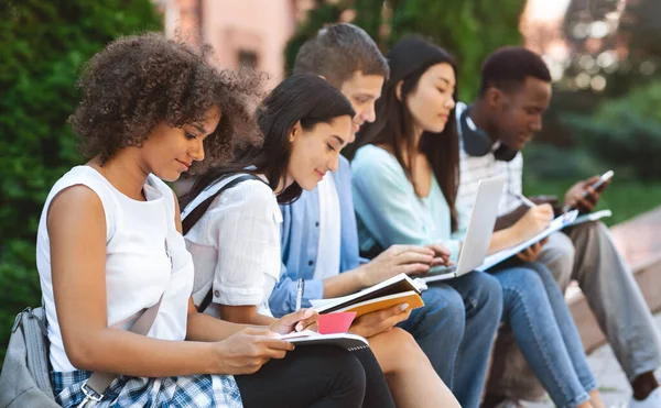 Utbildningsprocess. Grupp av studenter studerar utomhus med arbetsböcker och bärbar dator — Stockfoto