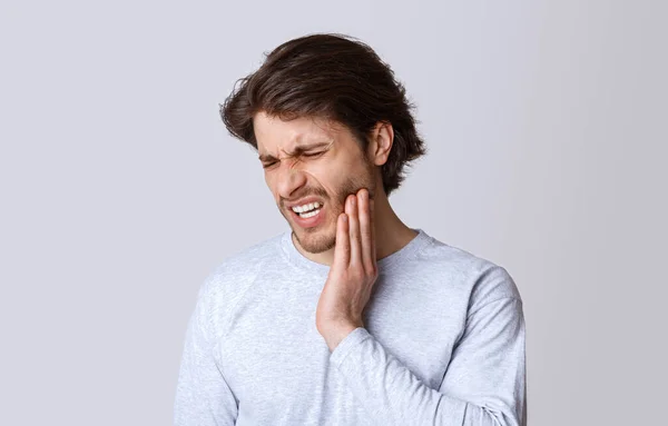 Doença dentária. Homem sente dor, caretas e pressione mão para bochecha — Fotografia de Stock