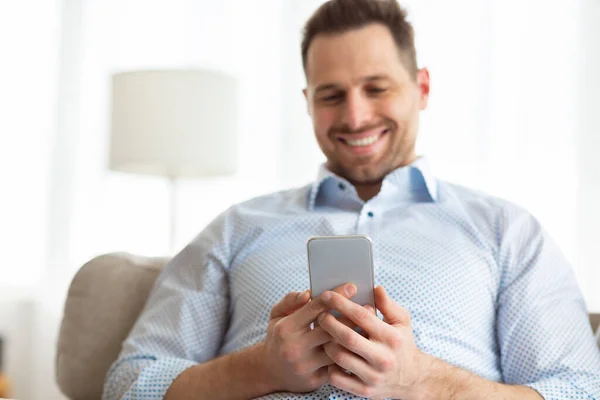 Cheerful adult man using smartphone at home — Stock Photo, Image