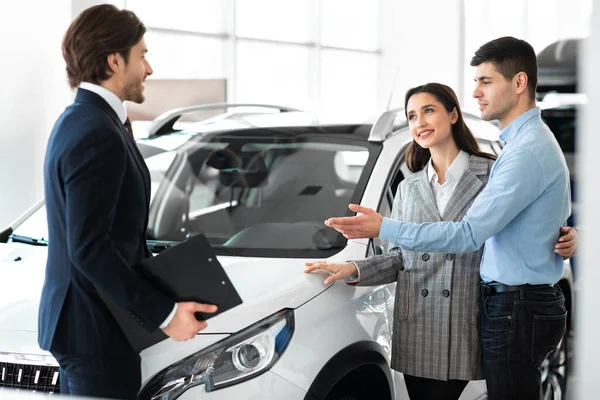 Pareja joven que elige auto con distribuidor profesional — Foto de Stock