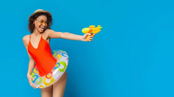 Summer Promo. Playful Girl In Swimsuit Aiming Water Gun At Copy Space — Stock Photo, Image