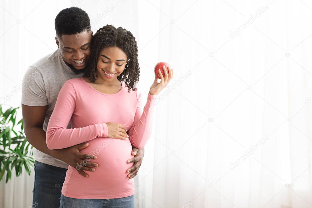 Black married couple cuddling at home next to window