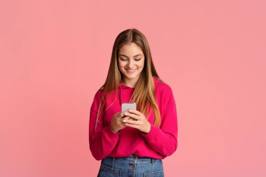 Mesajda iyi haberler var. Gülümseyen genç kız akıllı telefonu kontrol ediyor.
