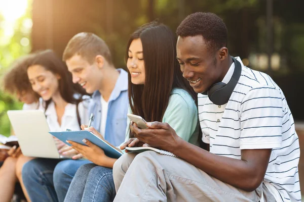 Multietničtí studenti se baví, společně studují na zkoušky venku v areálu školy — Stock fotografie
