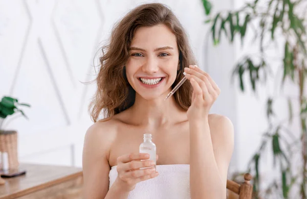 Menina feliz em toalha segurando soro facial — Fotografia de Stock