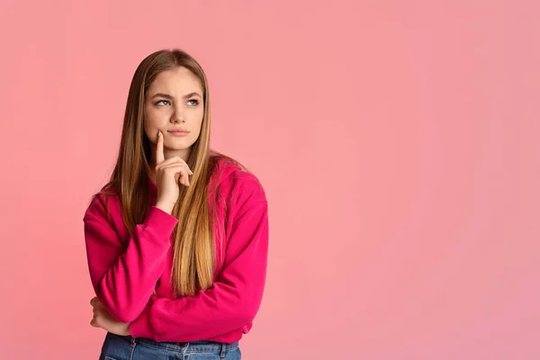 Interesting offer. Pensive girl puts finger to her chin and looks at empty space — Stock Photo, Image