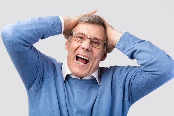 Emocionální starší muž křičí dotýkající se hlava pózující na šedém pozadí — Stock fotografie