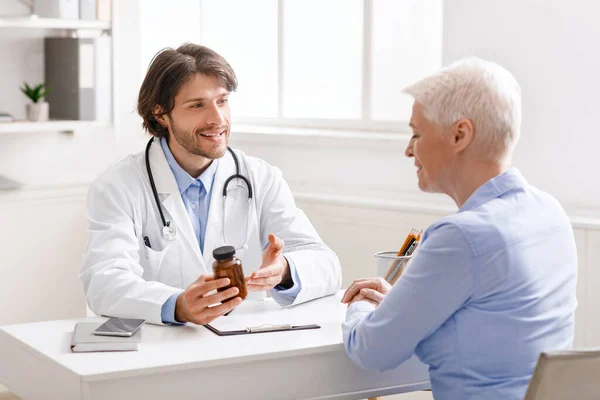 Junge Altenpflegerin erklärt Seniorin Tabletten-Plan — Stockfoto