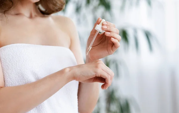 Primer plano de la mujer aplicando suero en la mano, probando el producto de belleza —  Fotos de Stock