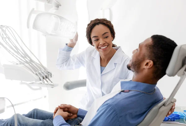 Female dentist turning on lamp before treatment — Stock Photo, Image