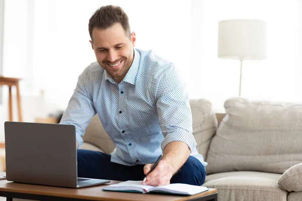 Hombre usando el ordenador portátil en casa y escribir notas — Foto de Stock
