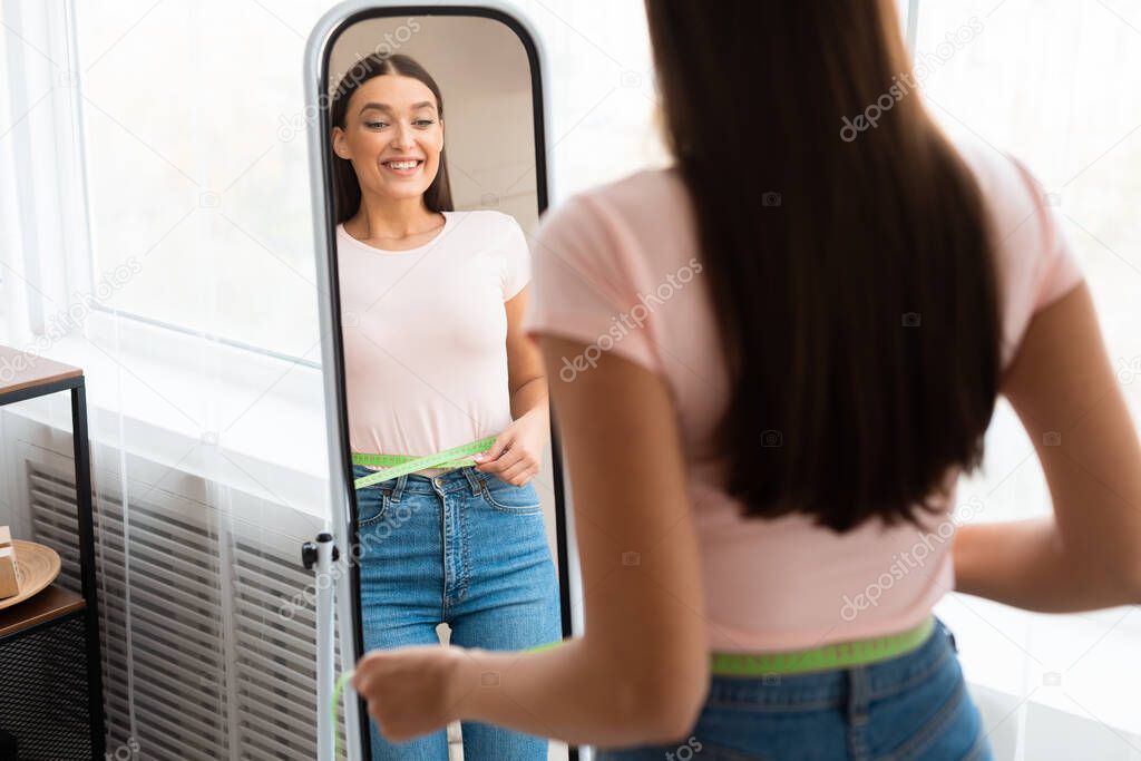 Excited Girl Measuring Thin Waist Looking In Mirror At Home