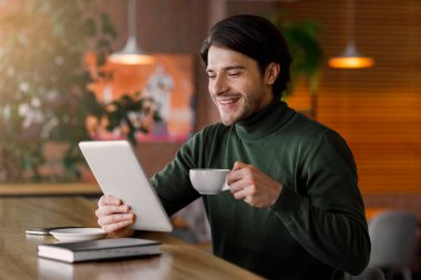 Kafede kahve içerken e-posta okuyan mutlu bir işadamı.