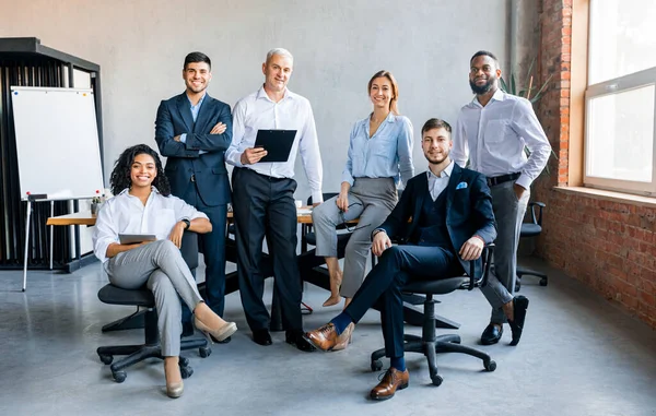 Colegas sorrindo para câmera posando no escritório moderno — Fotografia de Stock