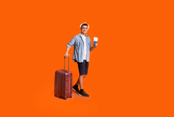 Чоловік турист з великою валізою, що тримає паспорт та квитки — стокове фото