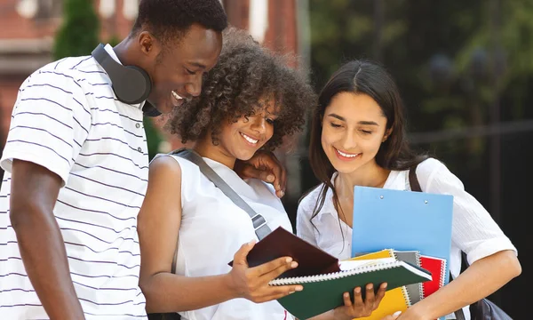 Estudiantes alegres estudiando al aire libre, de pie en el campus universitario, revisando el horario de las clases — Foto de Stock