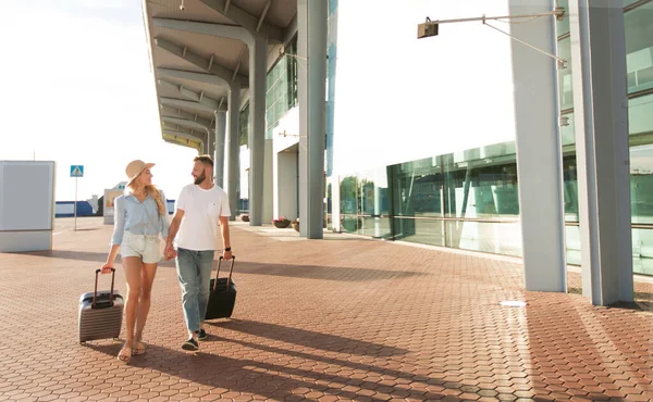 Pareja feliz caminando en el aeropuerto con equipaje, espacio para copiar — Foto de Stock