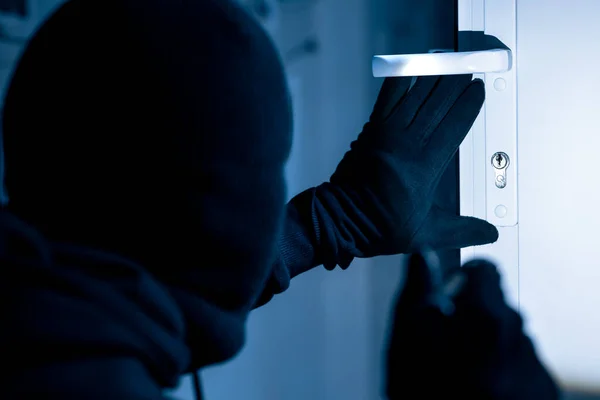 Ladrão no preto balaclava rachaduras porta com metal picklock — Fotografia de Stock