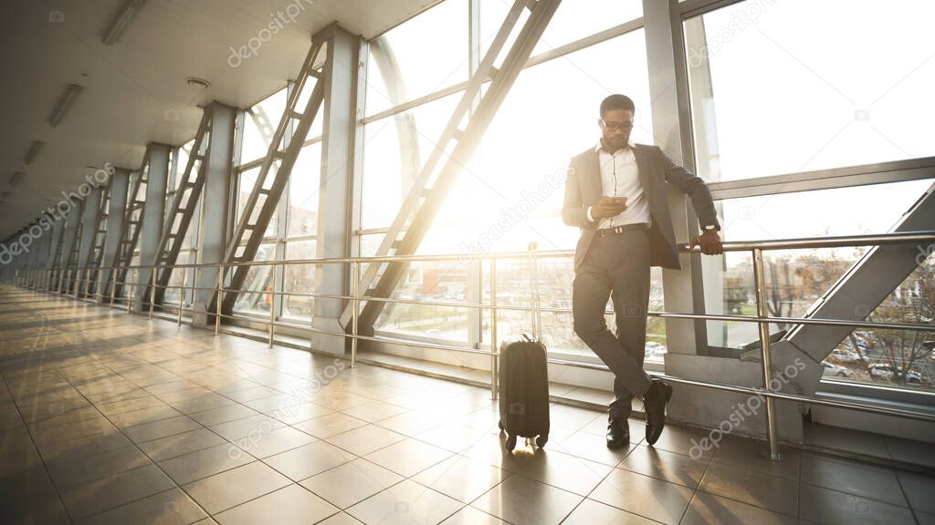 Black Entrepreneur Using Mobile Phone Waiting For Flight In Airport