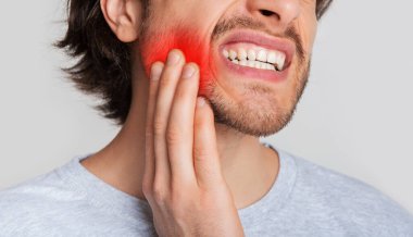 Diş ve diş eti iltihabı. Adam ağzında ağrıdan muzdarip ve elini kırmızı noktaya bastırıyor.