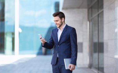 Şehir caddesinde ofis binasının yanında duran aletli başarılı bir bankacı.