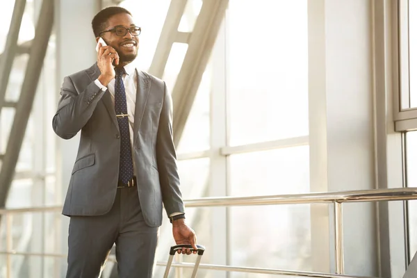 Feliz hombre de negocios hablando por teléfono caminando a través de la terminal del aeropuerto interior — Foto de Stock