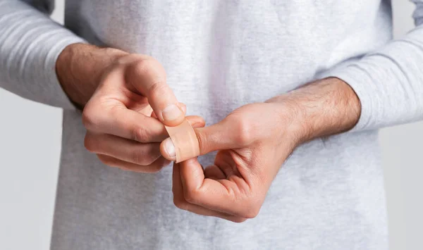 Wound, injury and pain. Man wraps his finger in band-aid — Stock Photo, Image