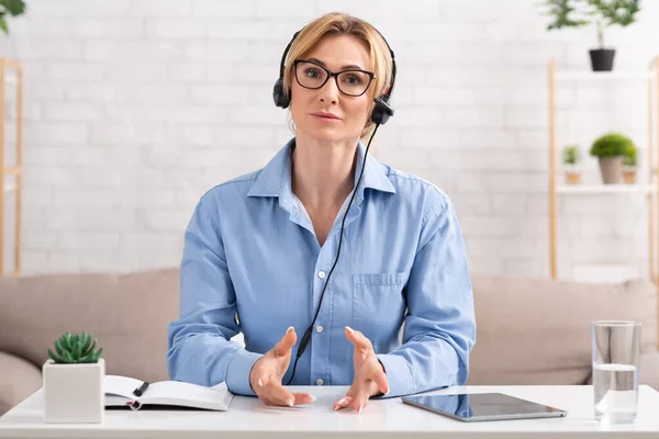 Berkomunikasi dengan klien melalui panggilan video komputer. Wanita dengan headset di tempat kerja — Stok Foto