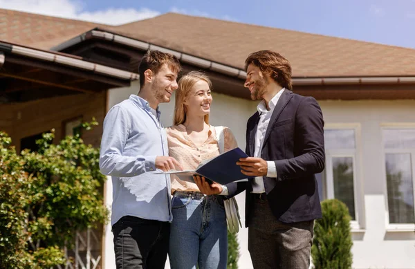 Real estate agent showing home rental or purchase contract to his clients in house backyard — Stock Photo, Image